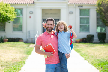 Father walking son to school. Parent and pupil of primary school with backpack.