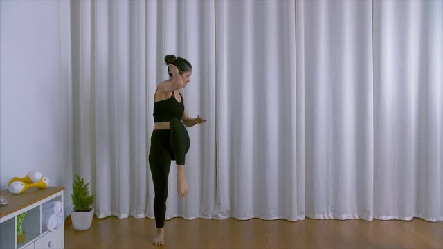 Young female trainer energetically doing Zuma exercises in her fitness studio. Indian sportswoman demonstrating Zumba dance workout for a healthy lifestyle at home - sports concept