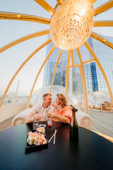 man and woman drink champagne and eat rolls in a rooftop cafe. 