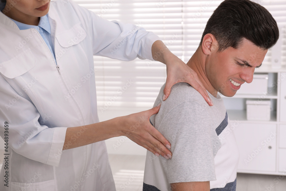 Sticker Doctor examining man with shoulder pain in hospital