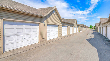 Pano Exterior of houses on a sunny day with white garage doors along paved road