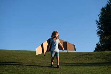 Child boy dreams and travels. Boy with airplane toy outdoors. Happy child playing with toy airplane outdoors in summer field. Travel, vacation and freedom concept. Kids leader skills.