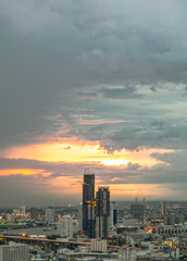 Fototapeta premium Bangkok, Thailand - 07 Jul 2021 : Aerial view of Beautiful sunset over large metropol city in Asia. There are prominent and isolated high-rise buildings along the Chao Phraya River. Selective focus.