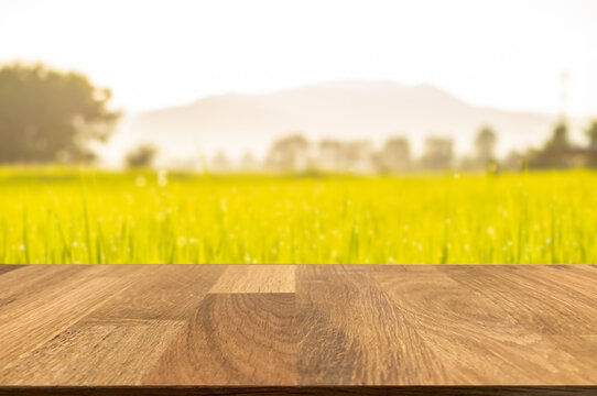 Empty wooden table top in front of blurred country side, organic rice field, mountains and beautiful sunlight background of nature. Can be used for display or montage for show your products.