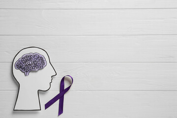 Human head cutout, brain and purple ribbon on white wooden background, flat lay with space for...