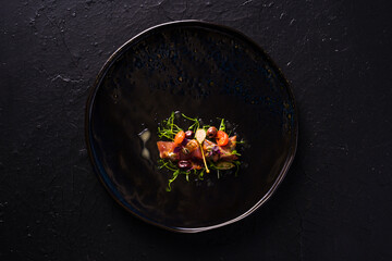 dish with marinated tuna, Taggiasca olives and capers. Dark background top view