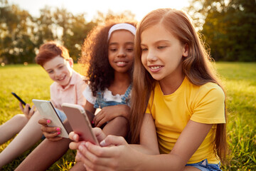 Multiracial kids using gadgets in park
