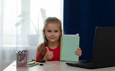 A little girl-child is doing homework. School stationery supplies. Distance education, home schooling, e-learning at home during quarantine