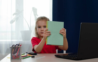 A little girl-child is doing homework. School stationery supplies. Distance education, home...