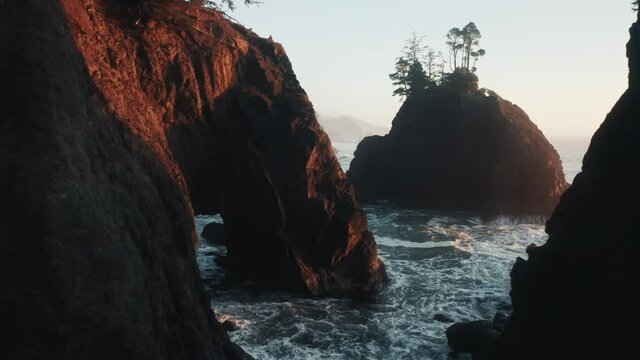 Drone flying close to narrow corridor of rocky sea cliffs and rocks at sunset 4K