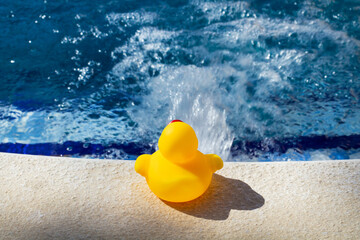 Pato de goma junto al borde de una piscina al aire libre. Vista de frente. Copy space