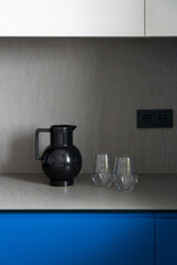 Stylish black jug with two glasses on kitchen countertop