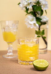 two glasses with a refreshing citrus drink or lemonade or alcoholic cocktail, a pair vintage goblets and cutting lime are arranged diagonally, minimalistic still life