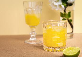 a crystal glass with a refreshing citrus drink or lemonade or alcoholic cocktail closeup, a pair vintage goblets and cutting lime are arranged diagonally, minimalistic still life, copy space