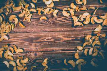 Slices of dried apples on a wooden background.