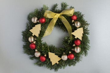 Fototapeta na wymiar Christmas ring or wreath with red and gold balls on the gray background. Top view. Close-up.