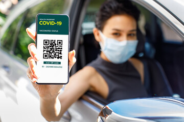 Woman in car show screen of smartphone with Covid-19 or coronavirus health passport vaccinated status and QR code sign to show she already get vaccine. Herd immunity concept