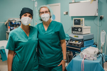 Portrait of medical nurses looking at camera inside operating theater at private clinic - Focus on...