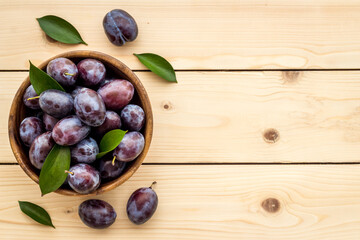 Food layout with plums in bowl with leaves. Top view