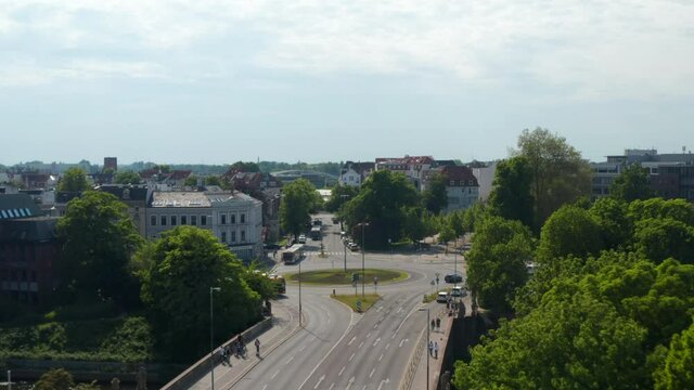 Forwards reveal of roundabout. Aerial view of main road with low traffic leading through town. Luebeck, Schleswig-Holstein, Germany