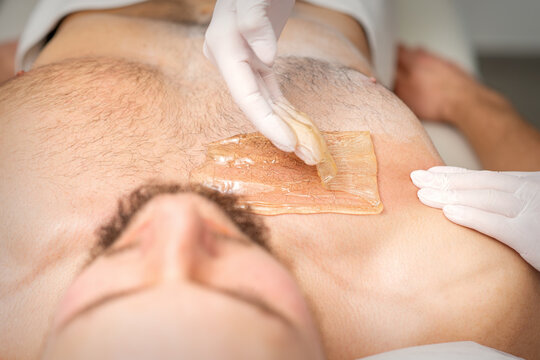 Young caucasian man receiving hair removal from his chest in a beauty salon, depilation men's torso