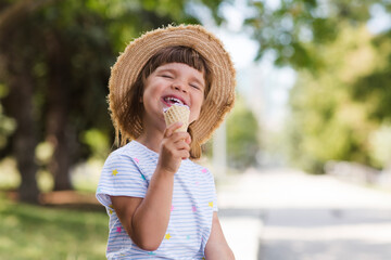 happy child girl  in sun hat eat ice cream in a summer park. Summer holiday
