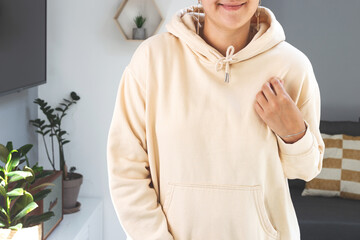 Woman wearing beige sweatshirt hoodie Mock up. Mother's day mockup in light home interior
