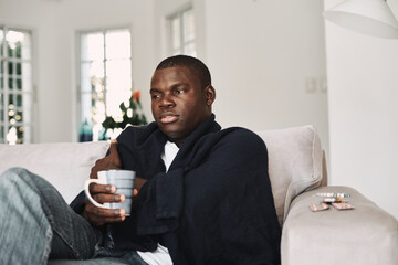 african-looking man sitting on the couch at home medicine health problem