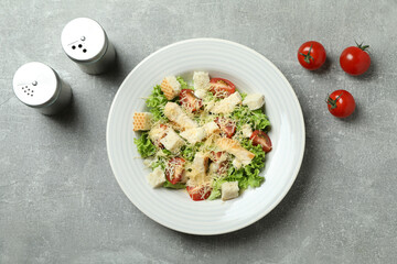 Concept of tasty eating with Caesar salad on gray textured background
