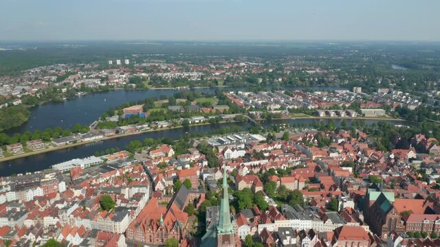 Aerial panoramic view of river dividing old town from other neighbourhoods. City surrounded by woods. Luebeck, Schleswig-Holstein, Germany