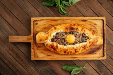 Georgian adjarian khachapuri with egg yolk and mushrooms