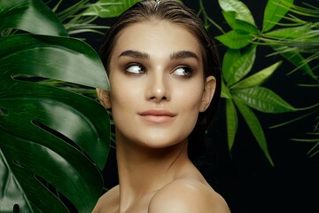 woman with bare shoulders green leaves exotic tropical