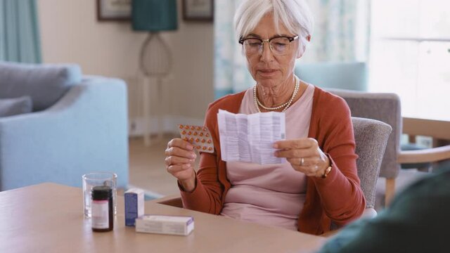 Senior woman checking medicine leaflet and taking a pill