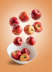 Red apples falling into a bowl