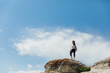 brunette woman standing on a cliff looking at the nature of the journey