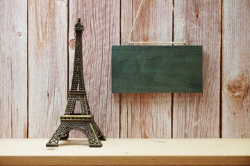 Empty wooden hanging on wooden background with eiffel tower home decor on wooden shelve