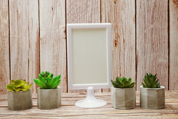 White mock up frame with Artificial Cactus and succulents decoration on wooden background