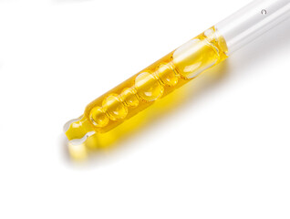 Glass cosmetic dropper with yellow serum.