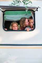 a mother and her children looks trhough the window of her caravan