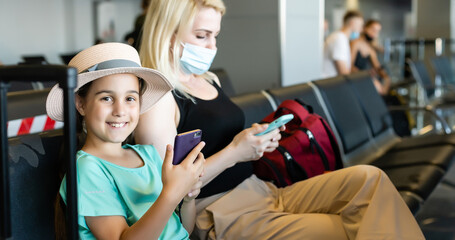 happy young mother with daughter at airport while waiting for their flight