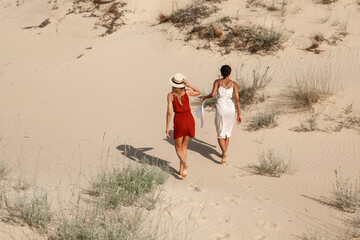 two women walk on hot sand in the desert in the summer