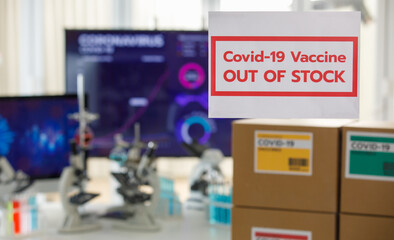 Selective focus on 'out of stock' for Covid 19 vaccines with covid 19 vaccines pack in boxes with separated colours label and microscopes in background . Concept for Covid 19 vaccination