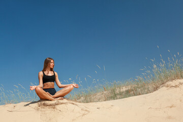 Fototapeta na wymiar woman in sportswear doing yoga on the sand in the desert in the summer