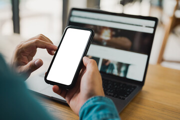 Top view close up man hands holding blank screen mock up mobile phone and using laptop computer. empty screen smartphone.