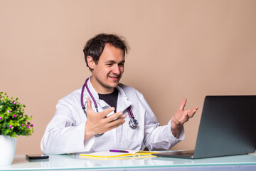 Male doctor works talking video call with patient using bast shoe while sitting at desk in back view clinic office.