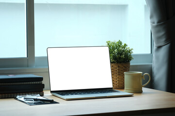 Mockup with blank screen of laptop computer on wooden desk, office desk concept.