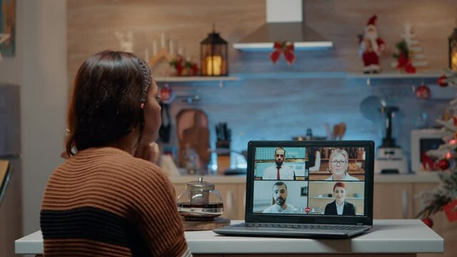 Woman on video call with workmates at home discussing job activities for meeting boss. Angry worker doing duties instead of celebrating christmas eve holiday. Person with online assignments