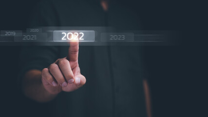 welcome year 2022 New year 2021 change to 2022 concept, businessman hand touching on 2022 virtual...