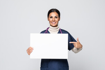 Young woman nurse or doctor in scrubs showing empty blank sign board with copy space isolated on...