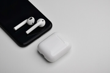 Wireless earphones, case for white headphones storage and charging, new phone on white background....